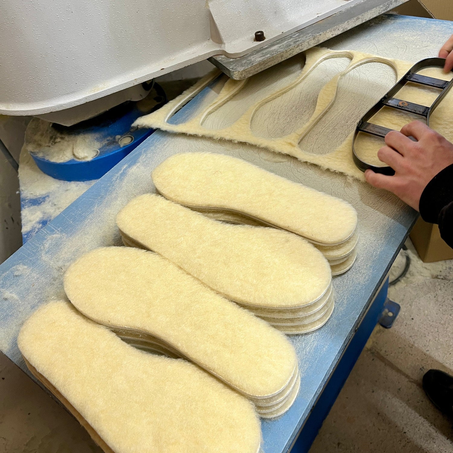 Lambswool Shoe insoles being cut out in a workshop setting.